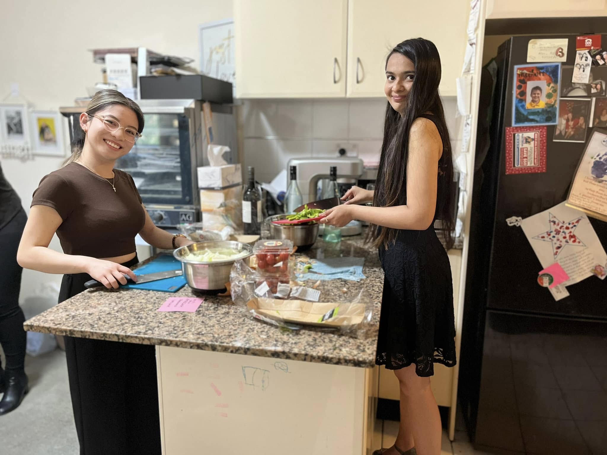 Two women preparing food together at a kitchen counter, part of an Empowered Oven cooking session